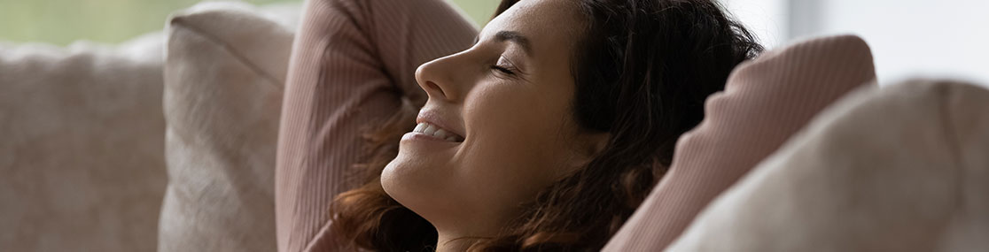 Woman happily lying on sofa breathing a fresh air